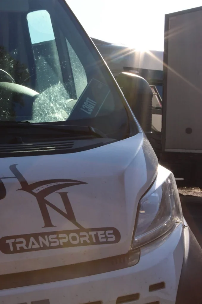 Detalhe da frente de uma carrinha HN Transportes em contraluz